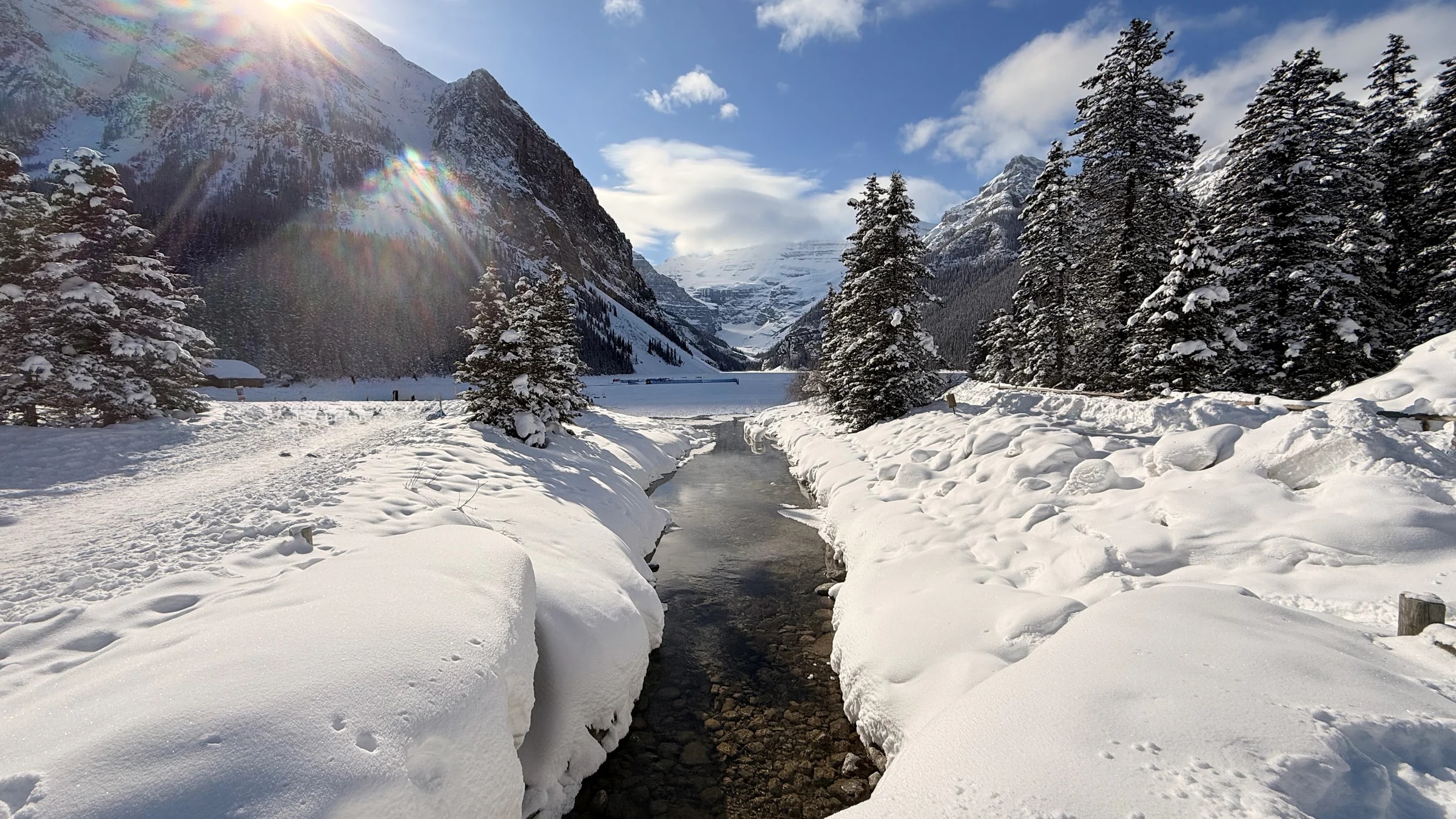 Snow-covered mountains above a small river winding through the valley